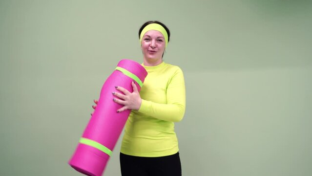 Female yoga teacher. Funny sport woman portrait. Bright fitness equipment. Confident workout lifestyle. One person with mat holding near head