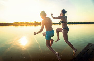 Fototapeta premium Mother and son spending time together on lake swimming and jumping in water.