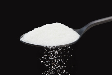 Falling natural white grains sugar on a black background. Shallow depth of field