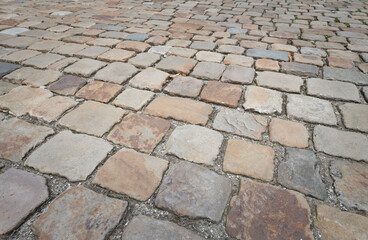 Background and texture of historic cobblestones made of stones that were individually hewn by hand. There is space for text.