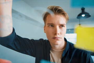 Professional caucasian businessman brainstorming marketing idea by using mind map and sticky notes on glass board at modern meeting room. Creative business and planing concept. Immaculate.