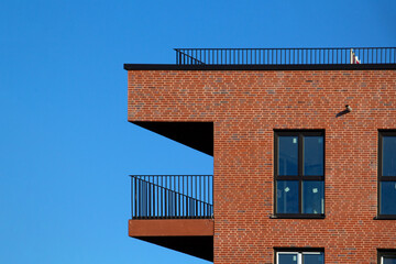 Modern Corner Facade with Red Brick, Balconies, and Windows. High quality photo