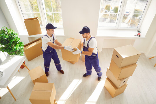 During relocation or delivery, two movers are seen carrying boxes into either a home or office space. Coordinated efforts reflect the professionalism of a relocation service.