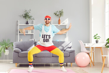 Happy, smiling guy exercising, dancing and having fun. Full body shot of cheerful, funny man in retro sports clothes doing dance moves with hands during fitness workout at home