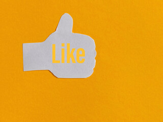 Hand icon thumbs up paper with like word on it with copy space background. Stock photo.