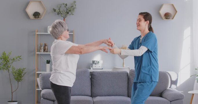 Caregiver or doctor happily dancing with an elderly patient at home, fun and enjoyable moment. Happiness, caregiving, and a warm connection between the nurse and the senior patient.