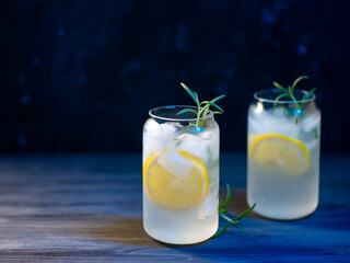 Gin tonic cocktail with lemon and rosemary. Two cocktails. Blue backlight