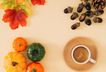 Autumn or fall scene made with cup of coffee, colorful autumn leaves, various pumpkins, pinecones and nuts with copy space on pastel beige background. Minimal autumn coffee concept. Nature flat lay.