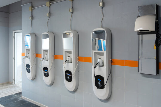 Automatic hair dryer station on public pool locker room wall with contactless reader for prepaid cards