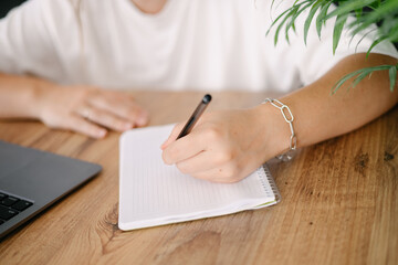 Woman writes by her left hand in a notebook