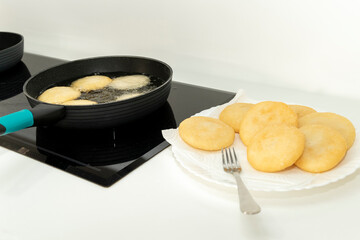 Freshly fried golden arepas sizzling in vegetable oil, with others ready for filling and eating, displayed in a beautiful kitchen setting. High quality photo