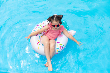 Little girl having fun on vacation at the hotel pool. Colorful vacation concept. Summer outdoor activity during family vacation in tropical resort. Beach and water toys. Sun protection.