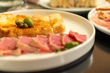 Green olives and capers on pieces of fried bread close-up on blurred background of delicious snacks