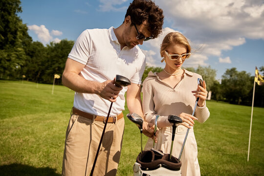 A young couple in elegant attire enjoying a game of golf on a lush green field at a prestigious golf club. - Powered by Adobe