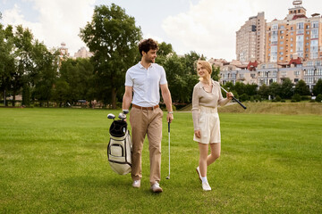 A young couple in elegant attire leisurely walk across a lush green golf course, enjoying a luxurious outdoor experience together.