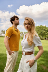 A stylish man and woman embrace in a lush green field, embodying an affluent and timeless...