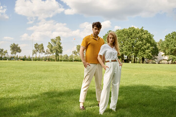 Fototapeta premium A beautiful young couple, dressed elegantly, standing together in a lush green field, exuding a sense of rich old-money luxury.