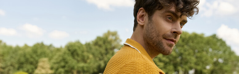 Obraz premium A man in a yellow shirt gazes confidently away in an outdoor setting, exuding style and charisma.