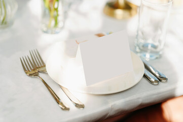 The table is elegantly set for an event with a blank place card, cutlery, and glassware arranged beautifully
