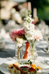 Beautifully arranged wedding table with delicate floral centerpiece and gourmet appetizers in an outdoor setting.