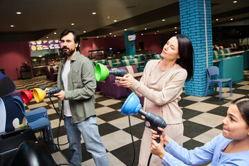 A happy family enjoying a game in a vibrant, bustling bowling alley on a weekend. © LIGHTFIELD STUDIOS
