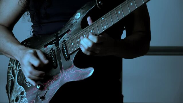 LONG HAIR GUITARIST PLAYING A SOLO ON HIS GUITAR IN SLOW MOTION FACE THE CAMERA