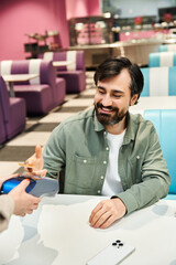 A man handing a credit card to a woman at a restaurant, symbolizing a seamless transaction in modern dining.