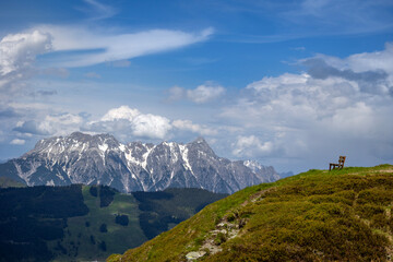 View on a mountain range in Austria, with a sitting bench