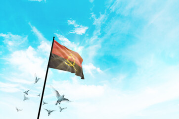 Angola flag waving with flying doves against sunset or sunrise. Angola flag for Republic Day and Independence Day.