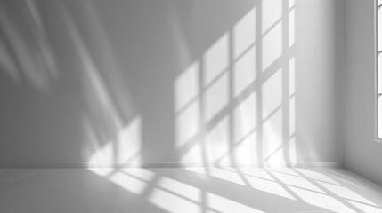 Obraz premium A bright, white wall and floor are illuminated by the sun shining through a window, casting a grid of light and shadow.