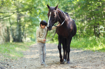Teenager boy kid with horse walking in summer forest, horseback riding