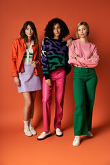 Fototapeta premium Three young, beautiful women, dressed in vibrant outfits, stand together in a show of unity and cultural diversity.
