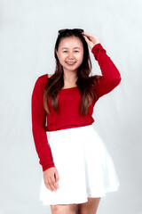 Beautiful young Asian woman wearing a red long t-shirt and white skirt is posing