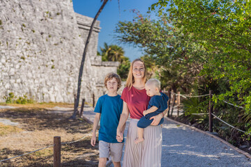 Mother and two sons tourists enjoying the view Pre-Columbian Mayan walled city of Tulum, Quintana...