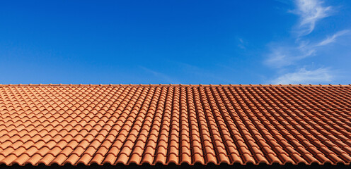 Clay tile roof. Banner with orange clay tile roof close-up on blue sky background with space for text, copy space