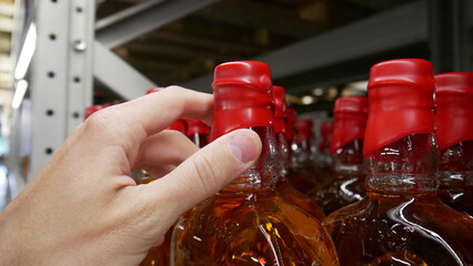 Close-up of a male hand taking a whiskey bottle with red sealing wax cork
