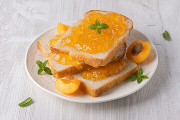 Toasts with tasty apricot jam on a white wooden table