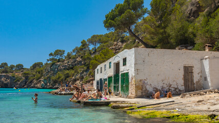 Tourists are enjoying the relax and peace at Cala Pi, surrounded by the cliffs and trees, mallorca, spain