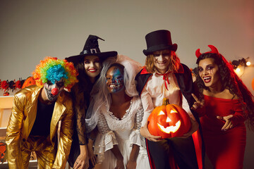 Happy young people dressed up as different spooky characters, with scary makeup on faces having fun...