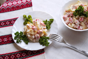 Homemade crab stick salad typical of modern Ukrainian cuisine and other Eastern European cuisines Traditional Ukrainian food on the table with embroidered tablecloth.