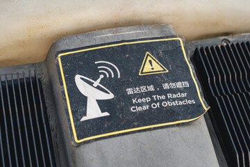A closeup of a radar warning sign sticker on the drone, with a satellite dish and an exclamation...