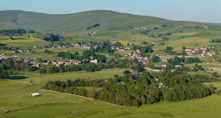 A scenic aerial shot capturing the essence of Hawes, nestled among vibrant green fields in the Yorkshire Dales, UK, reflecting rural beauty