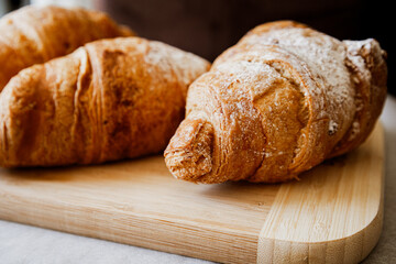 Crispy, fresh, homemade, oven-baked French croissant on a wooden plate; lots of croissants; coffee time; snack; cheat meal