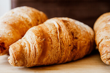 Crispy, fresh, homemade, oven-baked French croissant on a wooden plate; lots of croissants; coffee time; snack; cheat meal