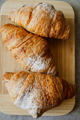 Crispy, fresh, homemade, oven-baked French croissant on a wooden plate; lots of croissants; coffee time; snack; cheat meal