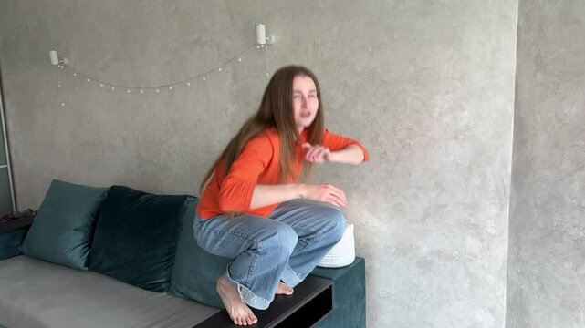 Young woman in casual clothing performs expressive interpretive dance in a living room. Creative, energetic, and artistic movement illustrating a range of emotions