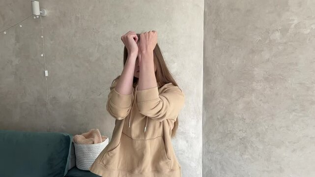 Young woman in casual clothing energetically lip syncs and dances indoors, showcasing joy and enthusiasm with expressive choreography and facial expressions