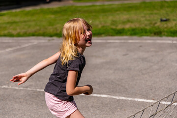 Young Girl Laughing While Playing a Game Outdoors on a Sunny Day