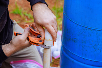 In course of installing water pipes, plumbers use special scissors to cut PVC pipe