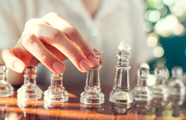 A woman is playing chess and is about to move a piece. strategic decision making and victory concept